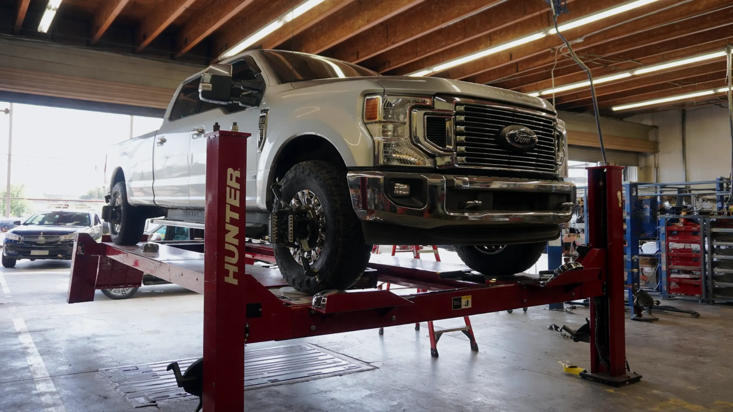 Professional suspension inspection and wheel alignment on lifted truck in automotive workshop