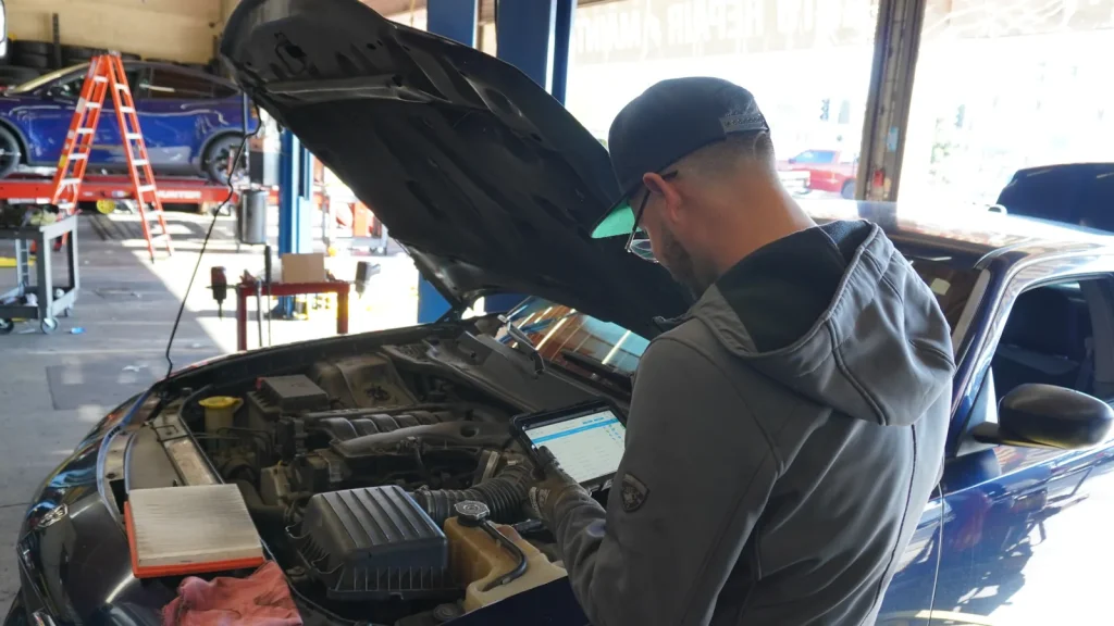 Comtires technician servicing an engine under the hood at our Ontario, CA shop